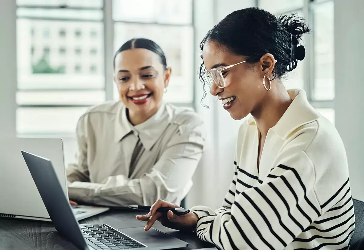 team of two people discussing marketing data at a laptop computer.