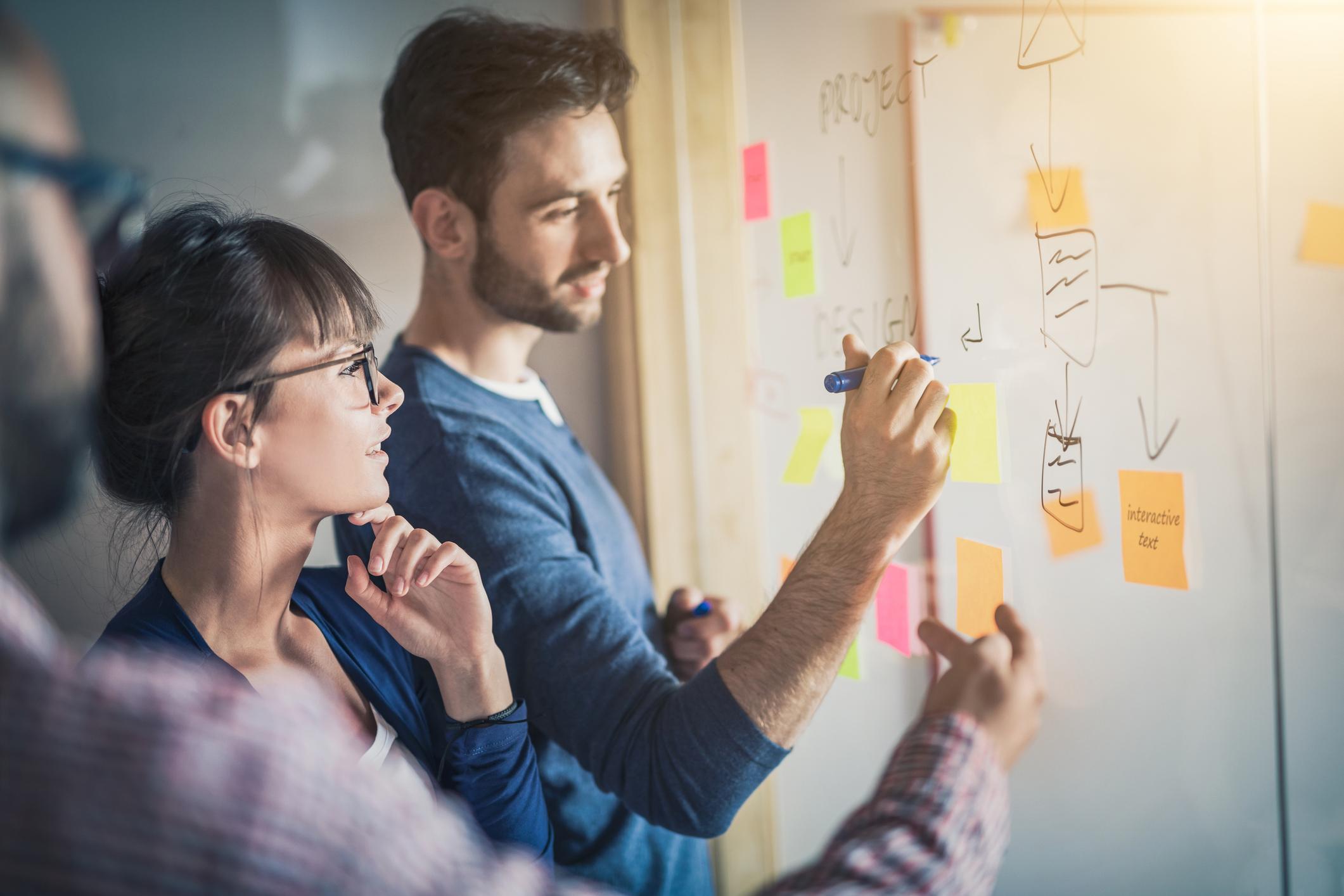 two people brainstorming together on a white board.