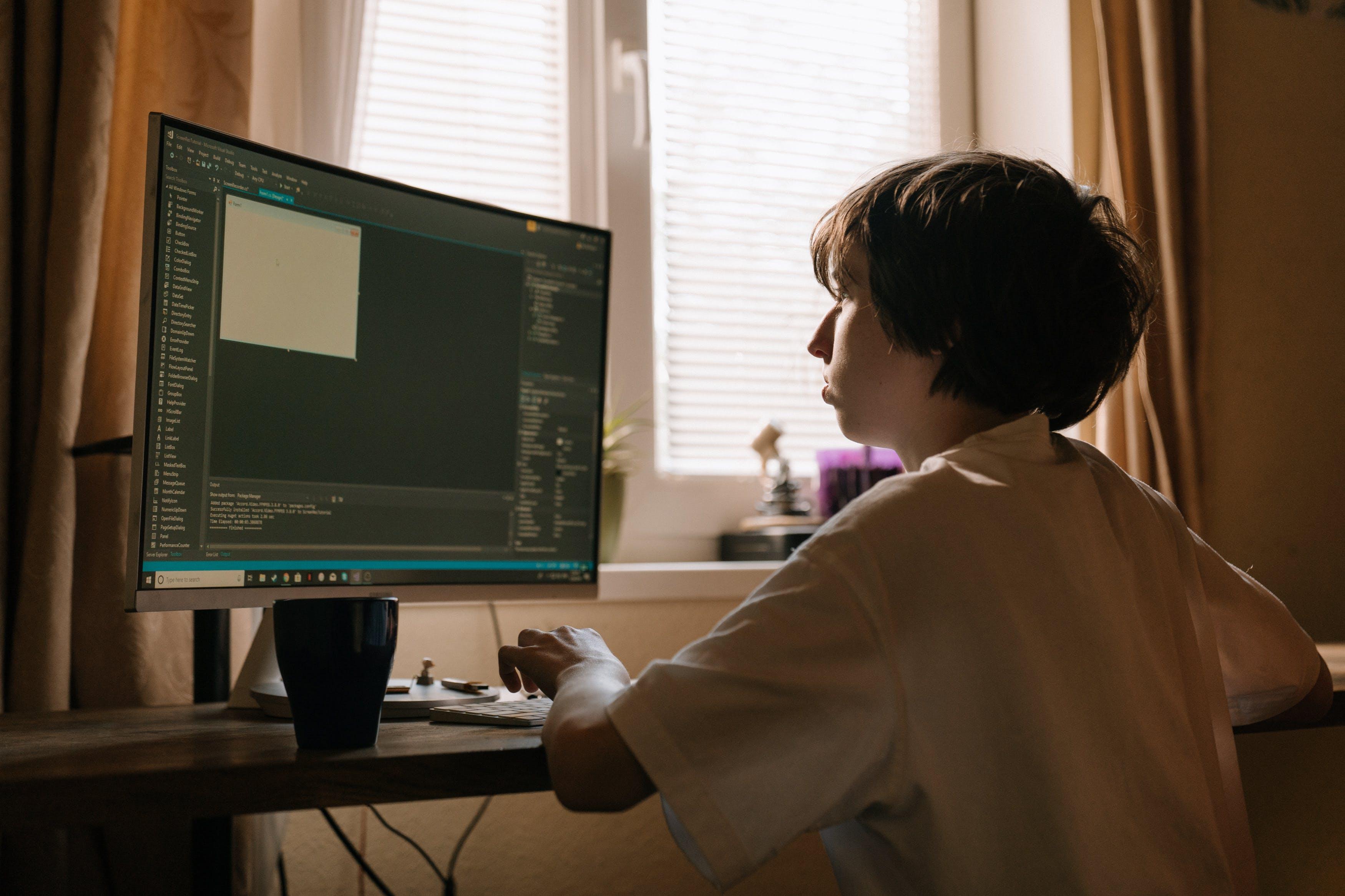 person sitting at computer coding