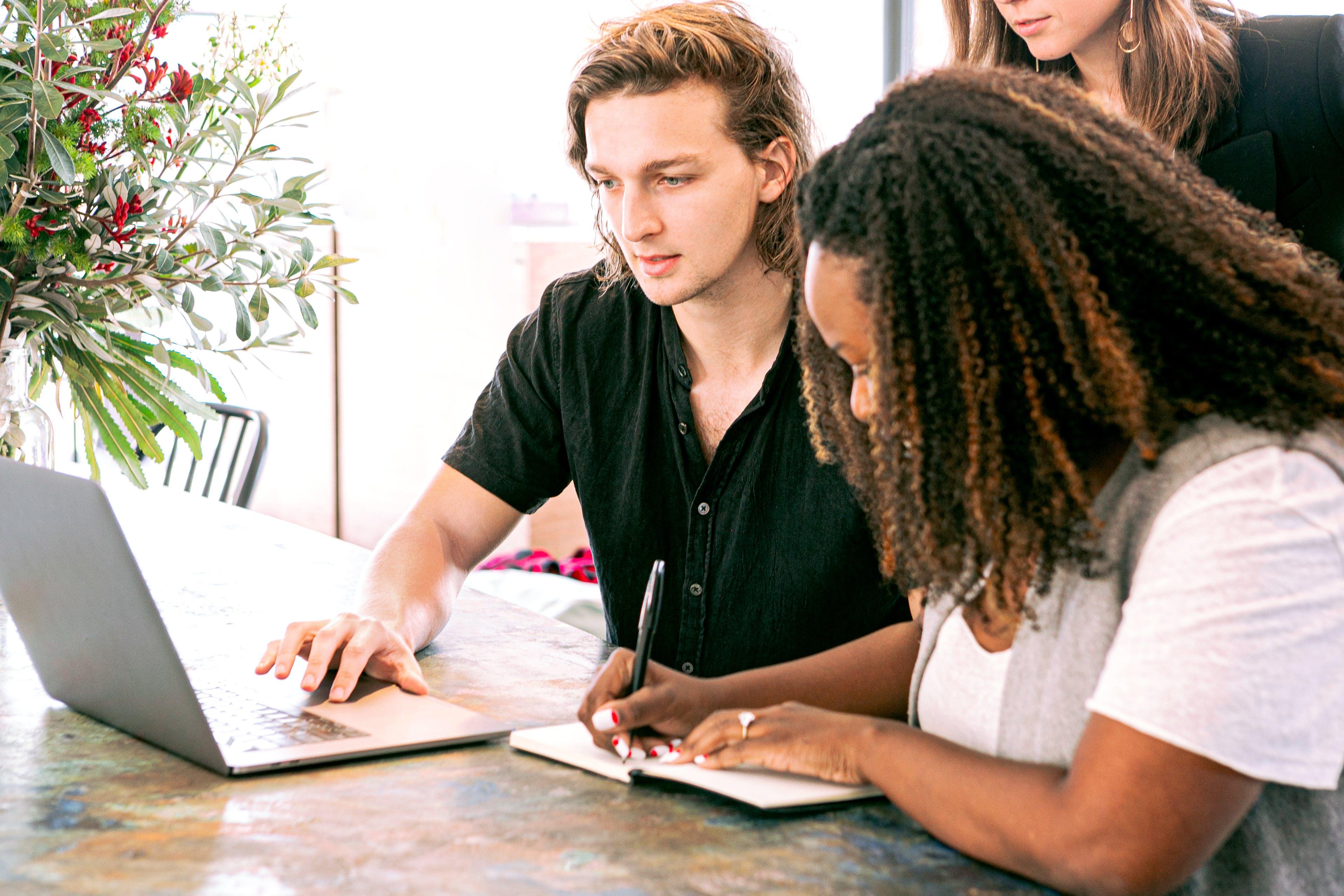 team of three people analyzing data on a computer at a table.