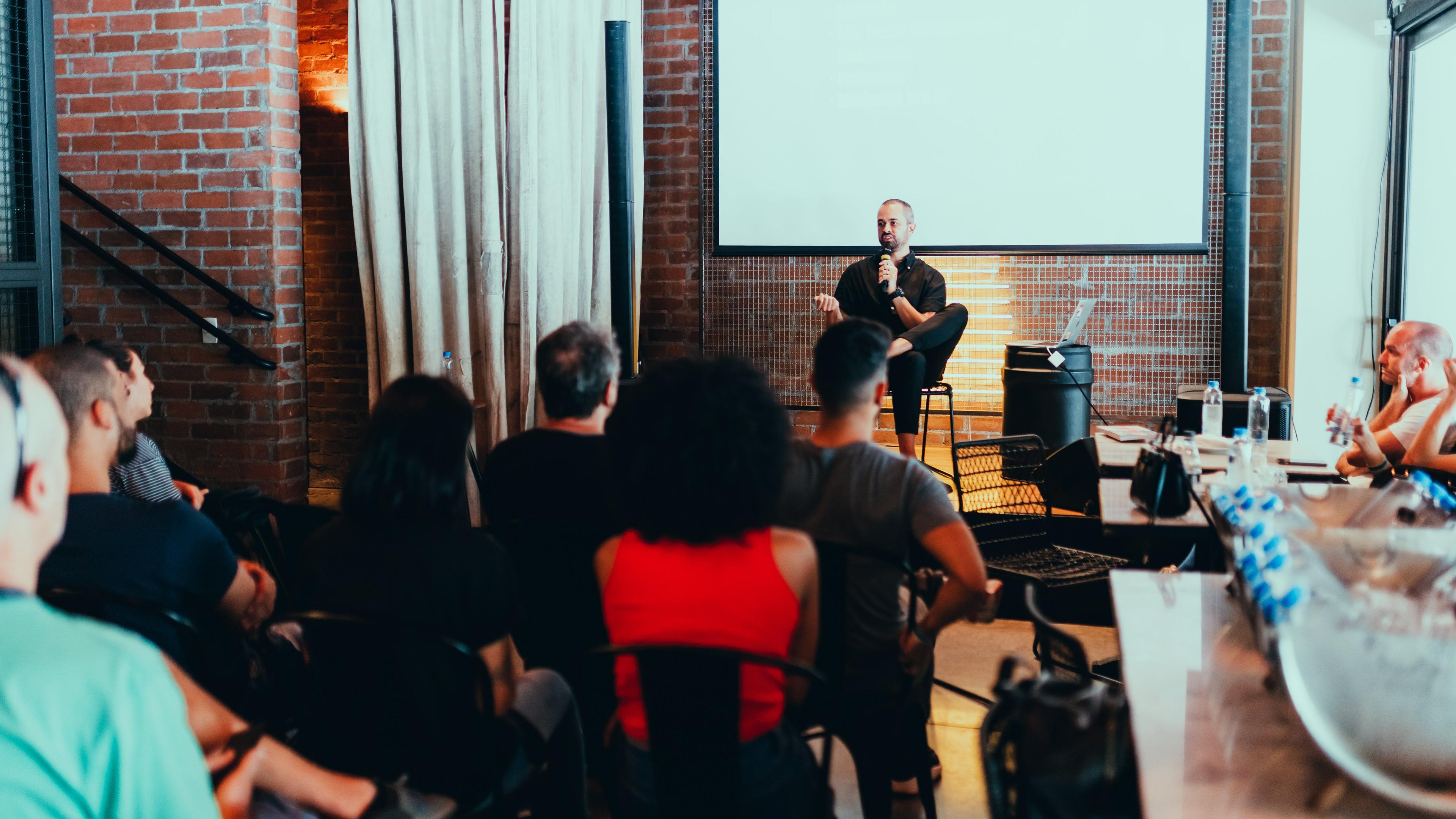 people sitting in a room at a conference with one person speaking at the front of the room