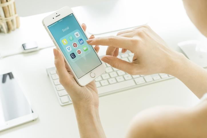 person holding a phone with several social media app on the screen